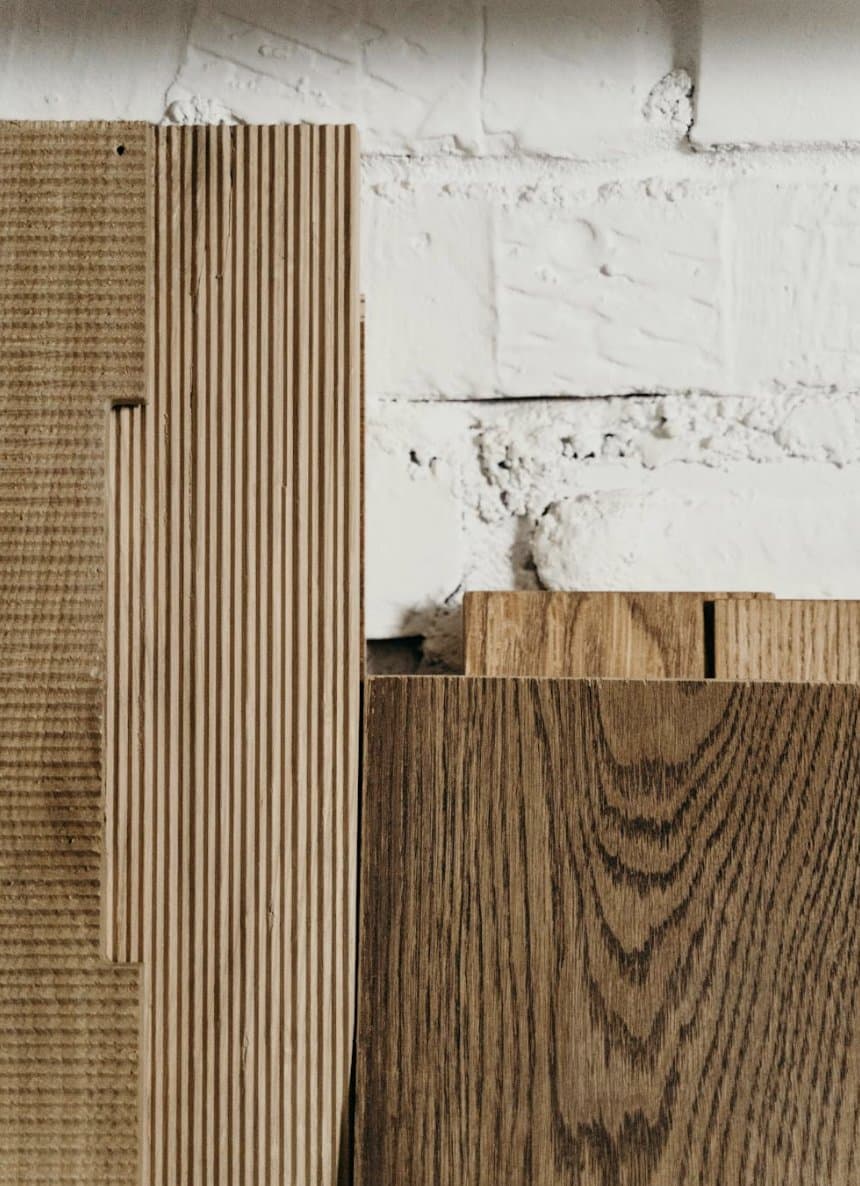 Samples of different types of wood leaning against a white brick wall
